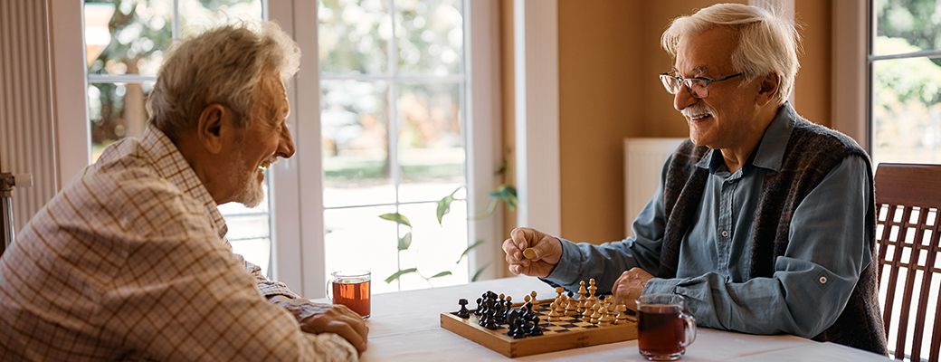 Image of two senior men playing chess and talking to each other